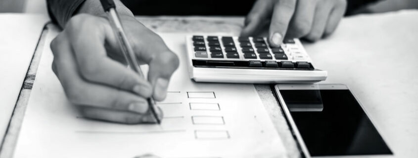 Finance person table's or workplace's close up a shot while he was doing some finance and loan-related work with cell phone, calculator and pages, and pen.